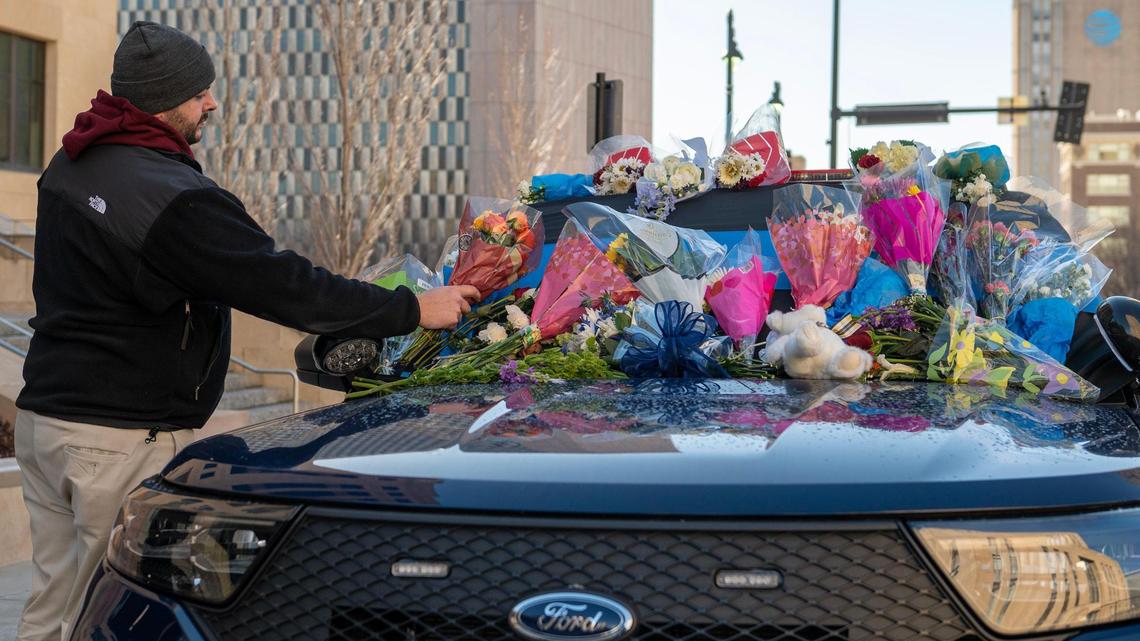 Tyler Colbert, a friend of Kansas City Police Officer James Muhlbauer, places flowers on a patrol car at KCPD Headquarters on Friday, Feb. 17, 2023. Muhlbauer and his K-9 police dog Champ were killed in a car crash Wednesday when a vehicle struck their patrol car. A pedestrian was also killed in the crash.