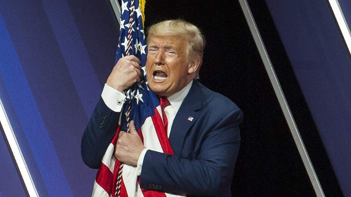 President Donald Trump hugs the US flag following his speech at CPAC 2020 at the Gaylord National Resort and Conference Center in National Harbor, Md., Saturday, February 29, 2020. The Conservative Political Action Conference (CPAC) is the largest gathering of conservatives in the world and features speakers including members of Congress, Vice President Mike Pence and President Donald Trump. (Photo by Rod Lamkey Jr./SIPA USA)