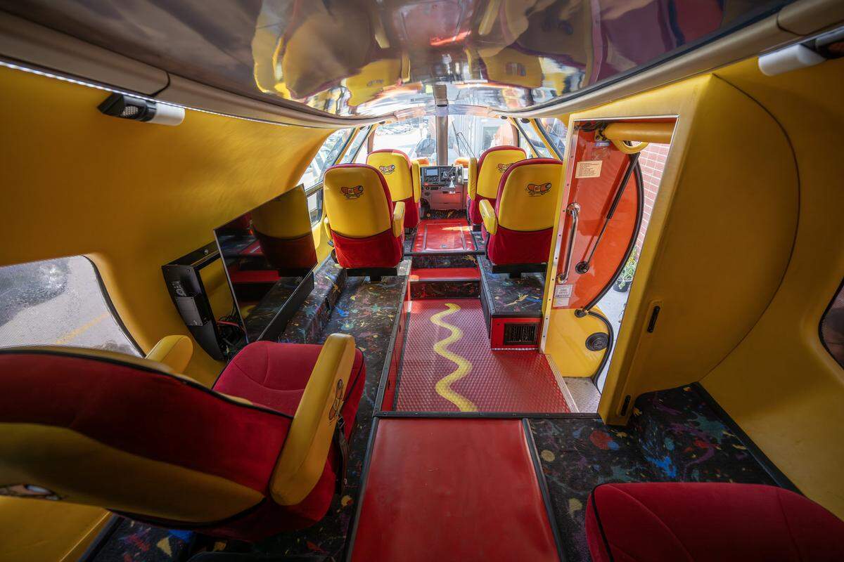 The interior of the Oscar Mayer Wienermobile features a red and yellow color scheme, including a mustard-yellow line along the walkway and vintage-patterned carpet, as the vehicle visits a local Hy-Vee on Friday, Aug. 8, 2025, in Lee's Summit.