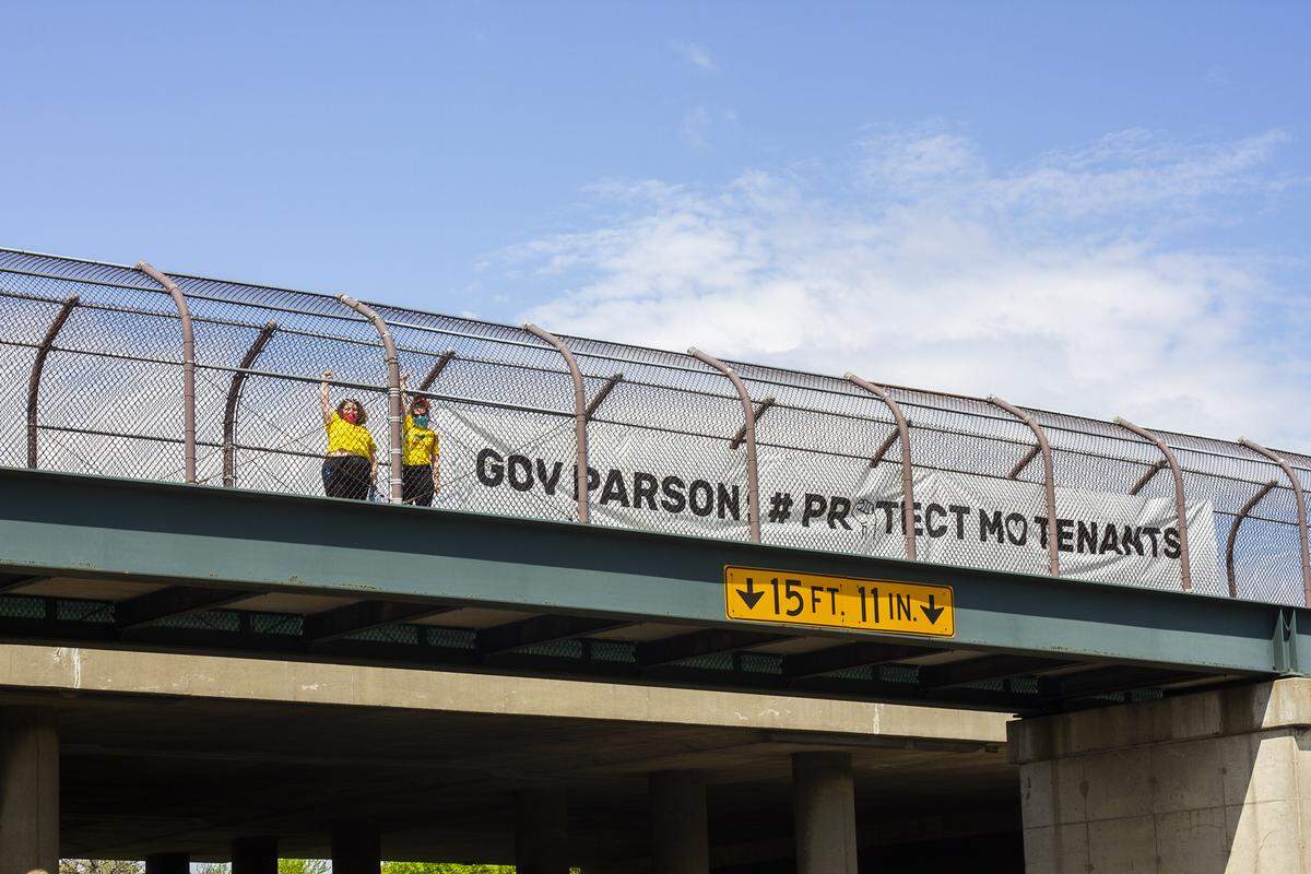 Members of the Coalition to Protect Missouri Tenants unfurl a banner on an Interstate 70 overpass near Columbia. The group wants Gov. Mike Parson to enact protections for tenants during the coronavirus pandemic.