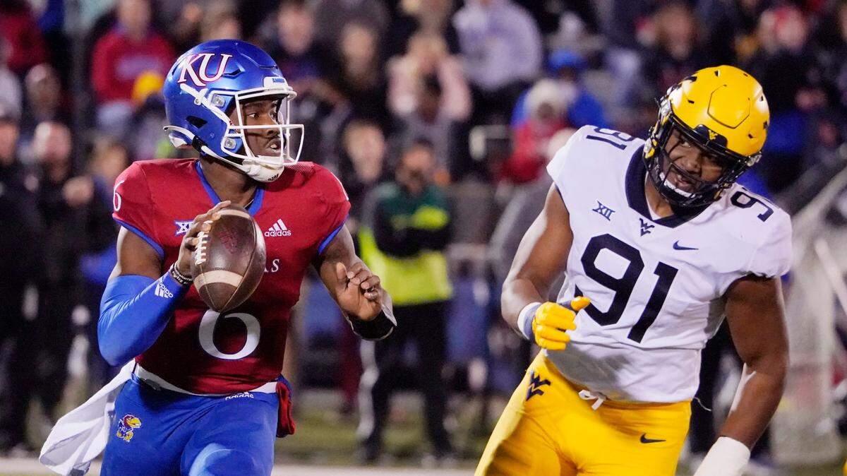 Kansas quarterback Jalon Daniels (6) looks to pass against West Virginia defensive lineman Sean Martin (91) during the first quarter of an NCAA college football game Saturday, Nov. 27, 2021, in Lawrence, Kan. (AP Photo/Ed Zurga)