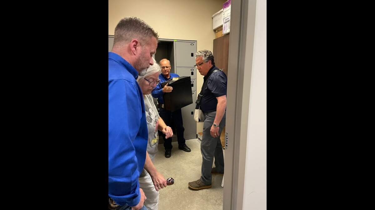 Marion County Sheriff Jeff Soyez, left, watched on Aug. 16, 2023, as a forensic examiner, right, took possession of items seized from the Marion County Record.
