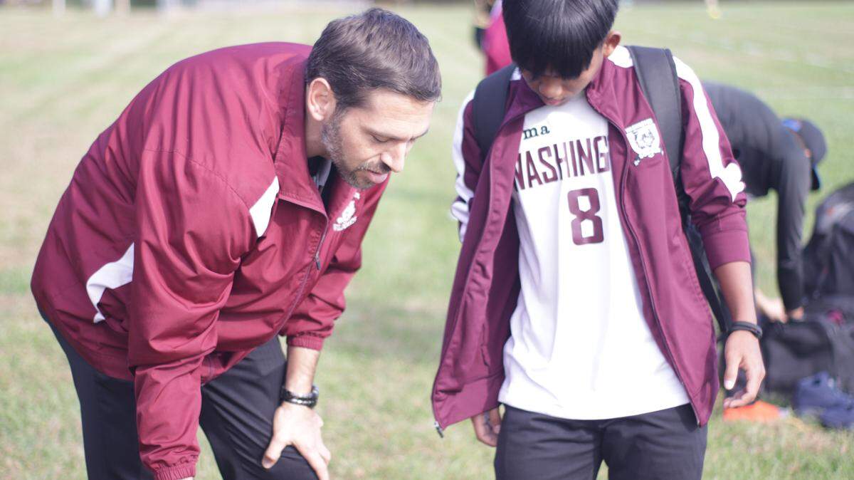 Washington High soccer coach Joseph Janner talks with one of his players, Ibzan Hmung, at a recent practice.