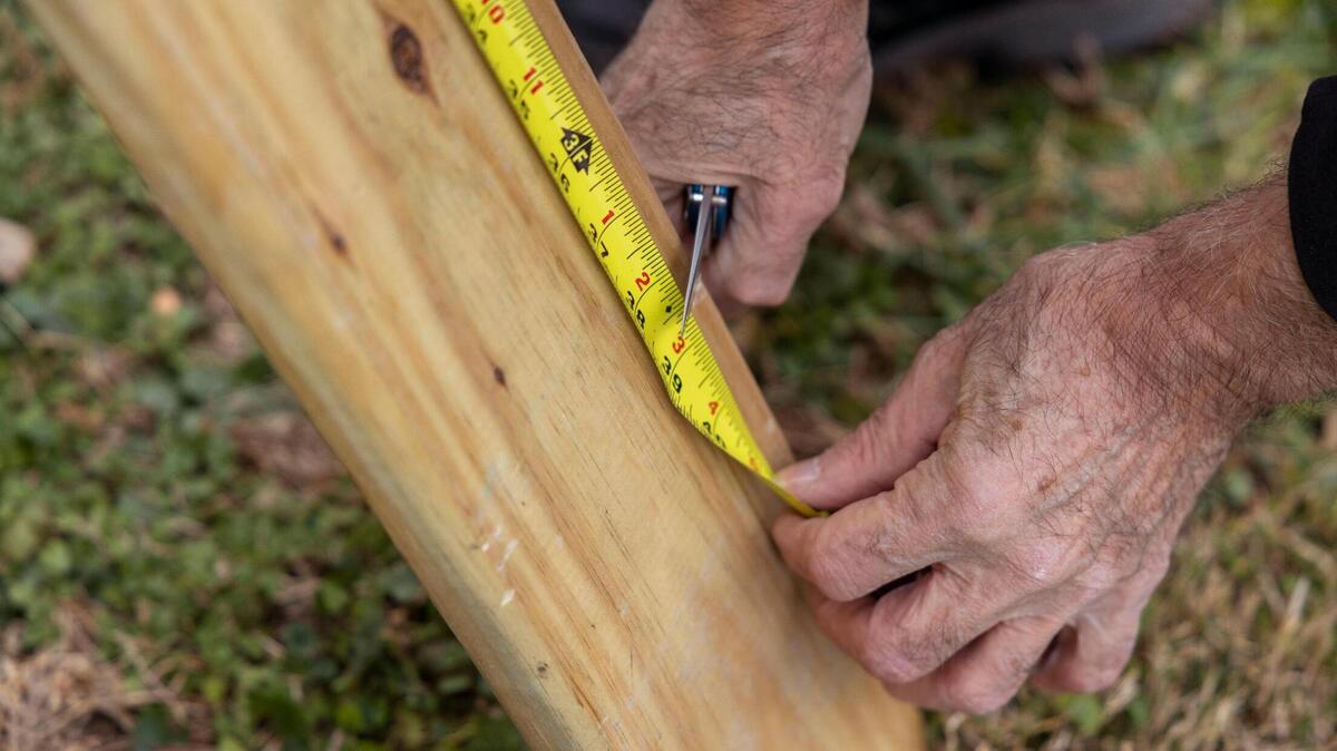 Robert Flores measures a piece of lumber while working on a deck repair for a resident on Dec. 17, 2021, in Kansas City, Kansas. Flores is chairman of Habitaciones Para Latinos Association (HPLA), an organization the makes free home repairs for those in need. 