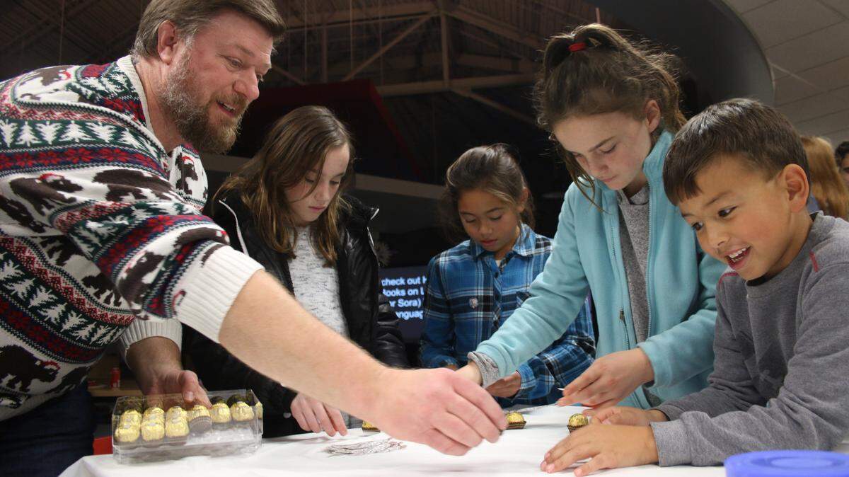 Lee’s Summit North librarian Michael Russell helps Macey Kruger, 11, Nadia Rose, 9, Mylah Kruger, 9, and Walker Rose, 7, make golden snitches out of Ferrero Rocher pieces at Harry Potter Literacy Night.