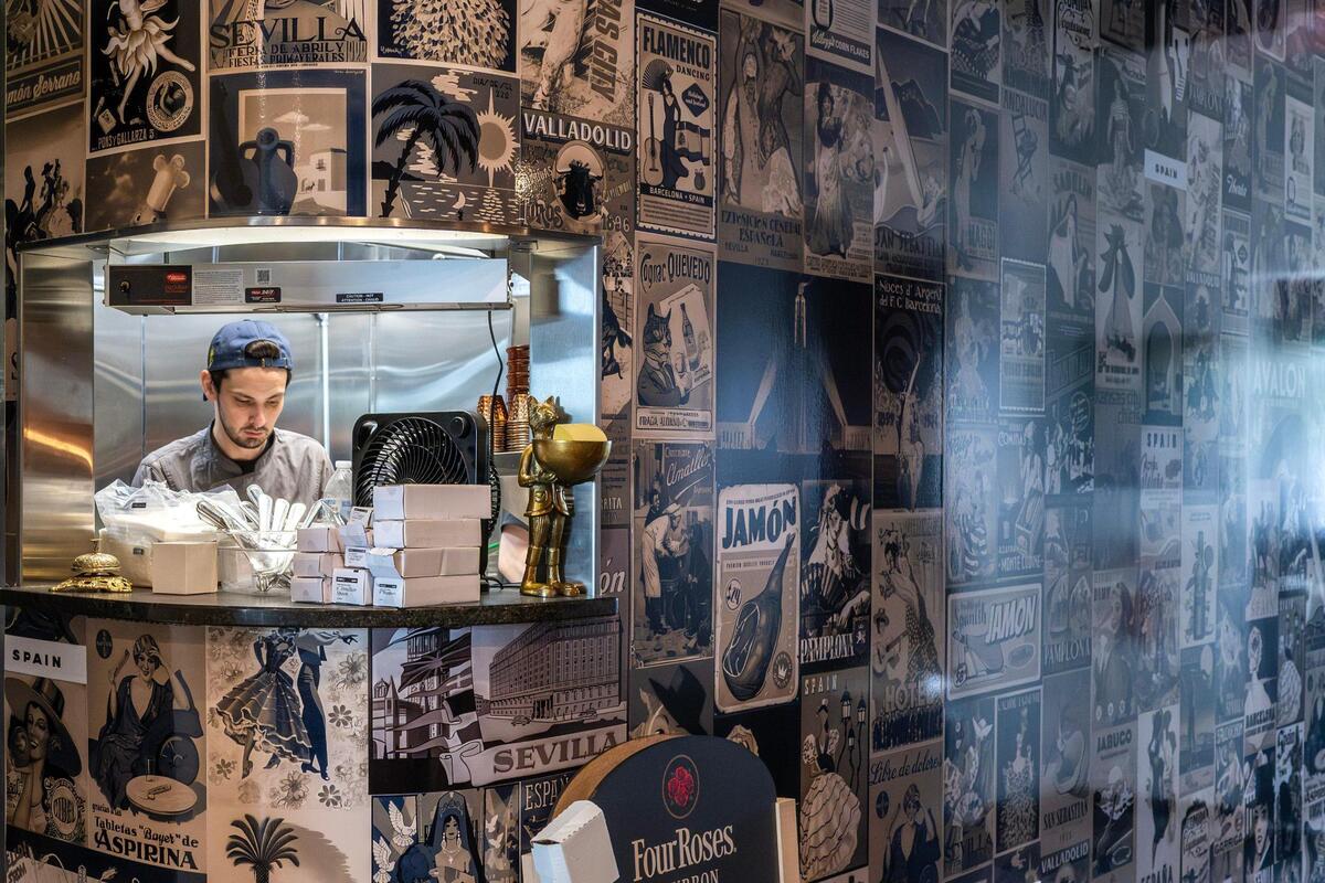 The kitchen area at Gilda’s Bar de Tapas, decorated with black-and-white wallpaper featuring vintage Spanish posters, is seen on Thursday, July 17, 2025, in Shawnee.