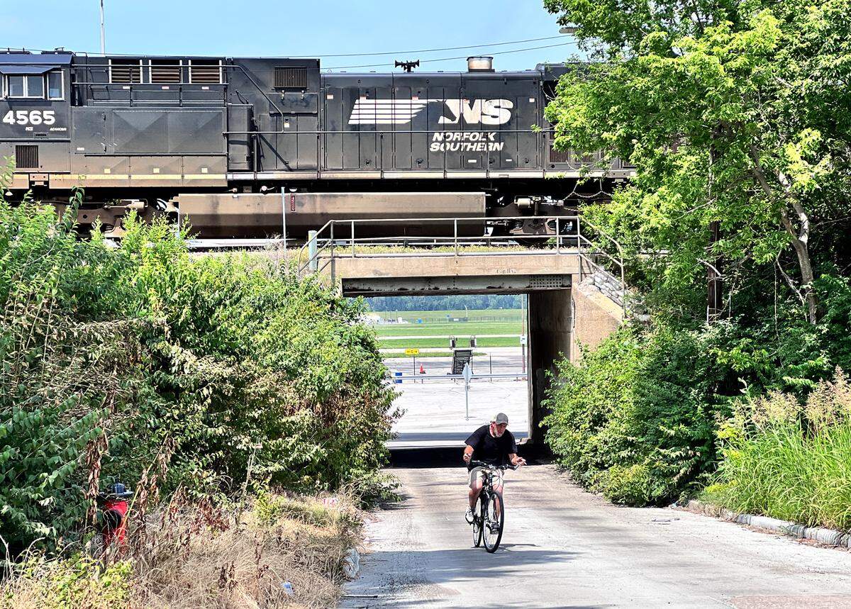 As a train passes overhead on an overpass, a bicyclist makes his way into Harlem after passing through a tunnel leading from the downtown airport.