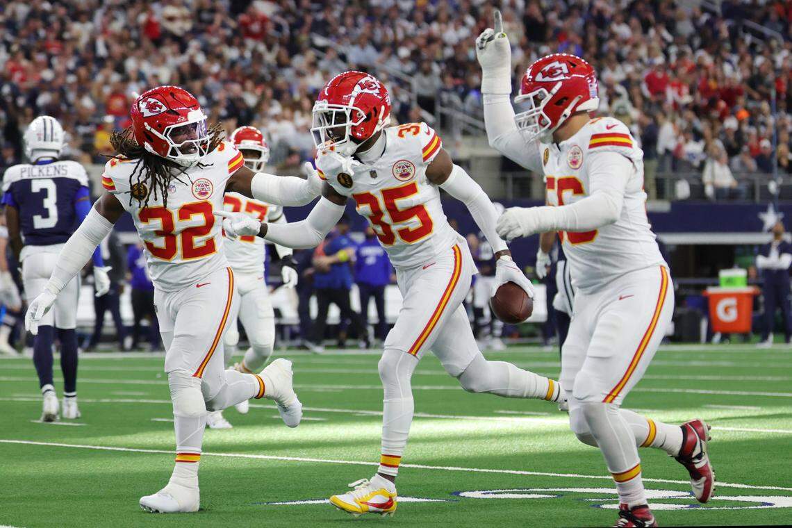 Kansas City Chiefs teammates Nick Bolton (No. 32) and George Karlaftis (No. 56) celebrate with cornerback Jaylen Watson (No. 35) after Watson made an interception during an NFL Week 13 Thanksgiving Day game against the Dallas Cowboys at AT&T Stadium in Arlington, Texas on Thursday, Nov. 27, 2025.