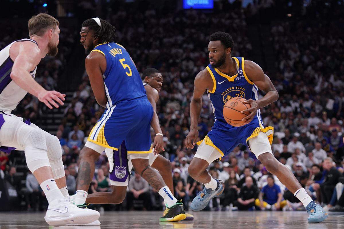 Golden State Warriors forward Andrew Wiggins, right, dribbles upcourt during a game against the Sacramento Kings in the 2024 NBA Playoffs.