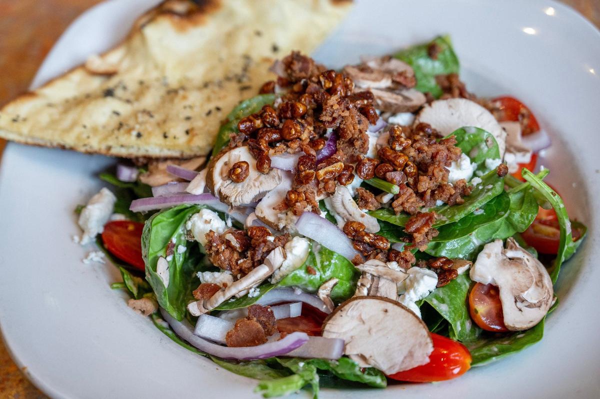 The goat cheese and candied pecans shine in Spin! Pizza’s spinach and goat cheese salad.