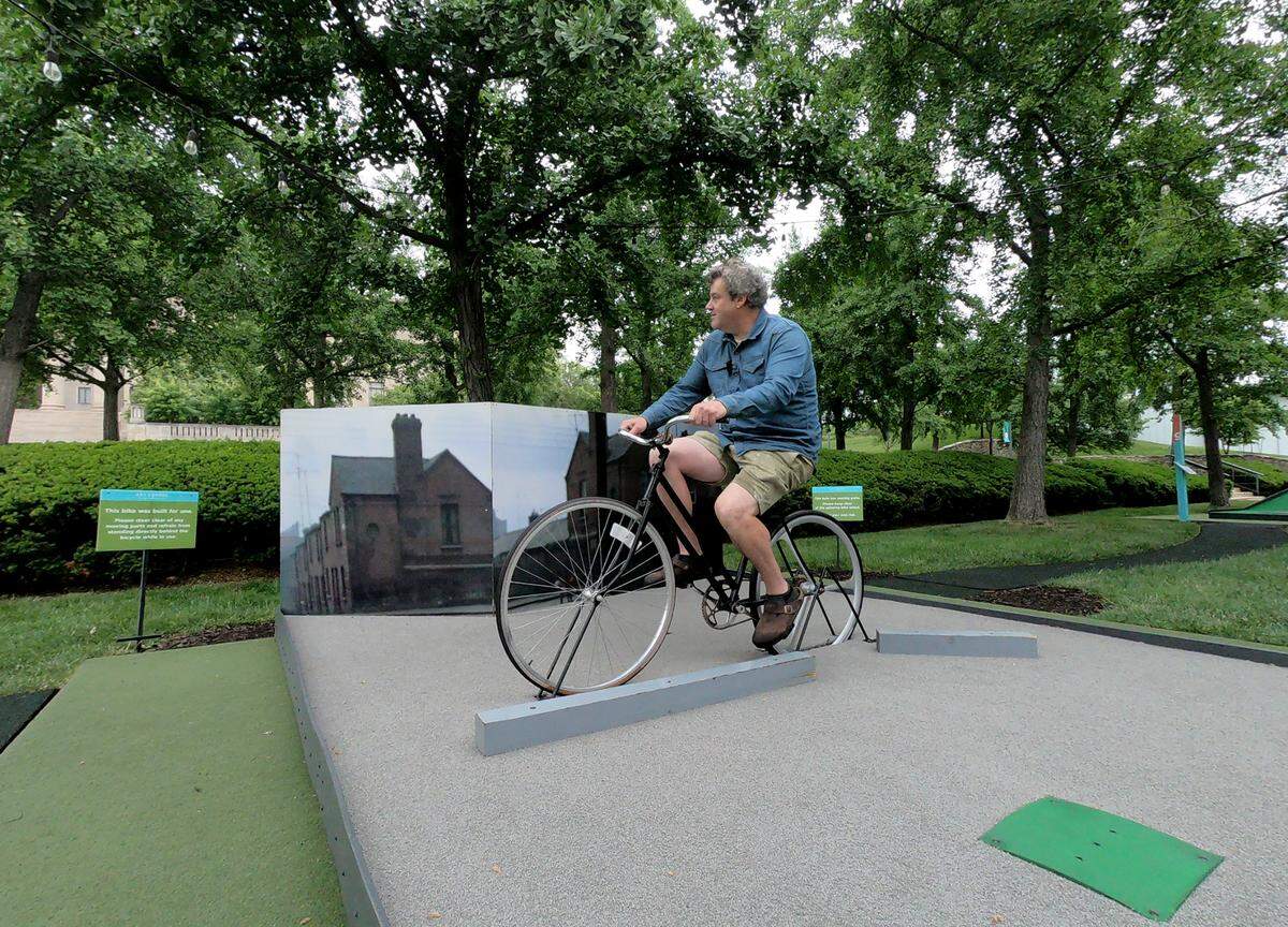 James Throckmorton, owner of Small Planet Gardens, demonstrates how golfers hit the ball between the spokes on the back wheel of a bicycle on hole 8, “Pedal!” at the Art Course, a nine-hole putt-putt golf course at the Nelson-Atkins Museum of Art. Each of the nine holes was inspired by a work of art in the museum’s collection.