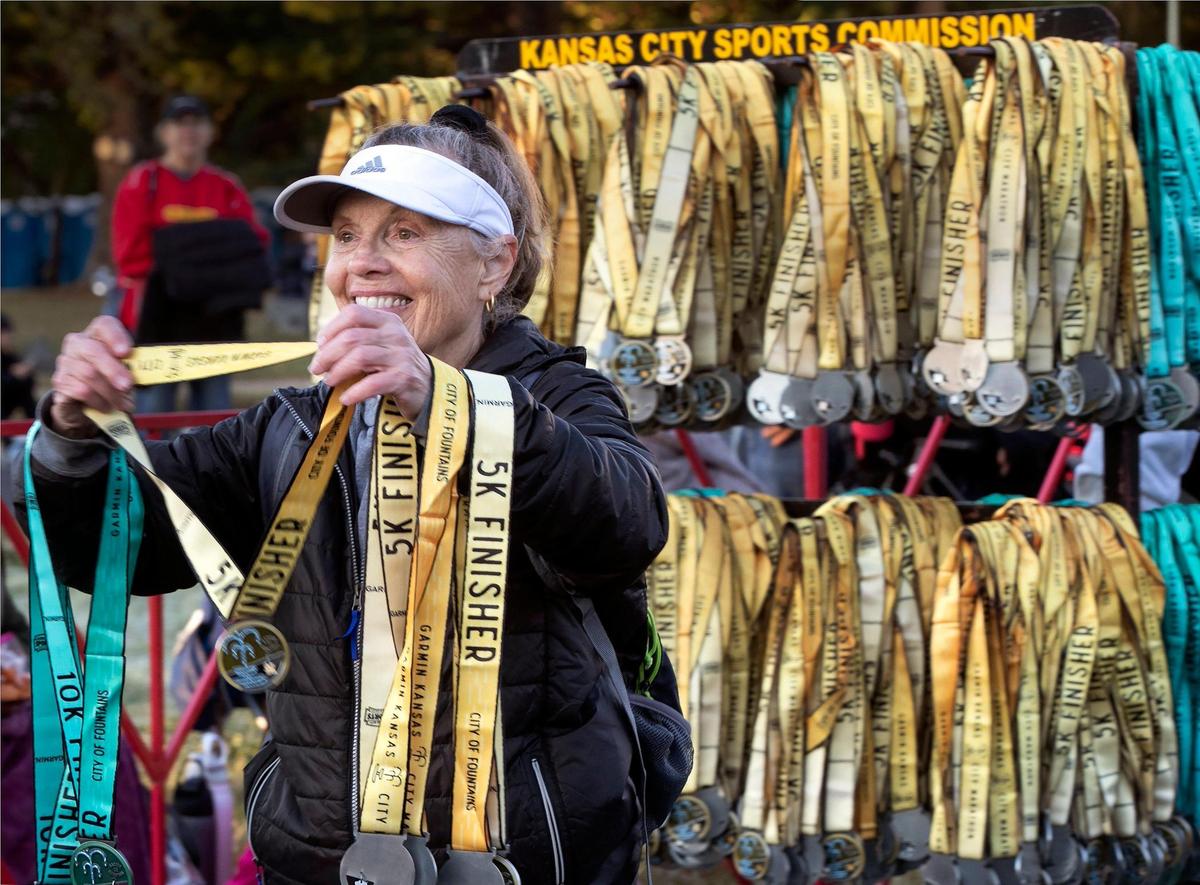 Volunteer Jodie Spielman of Overland Park greeted finishers with a smile and a medal during the 2024 Garmin Kansas City Marathon on Saturday, October 19, 2024.