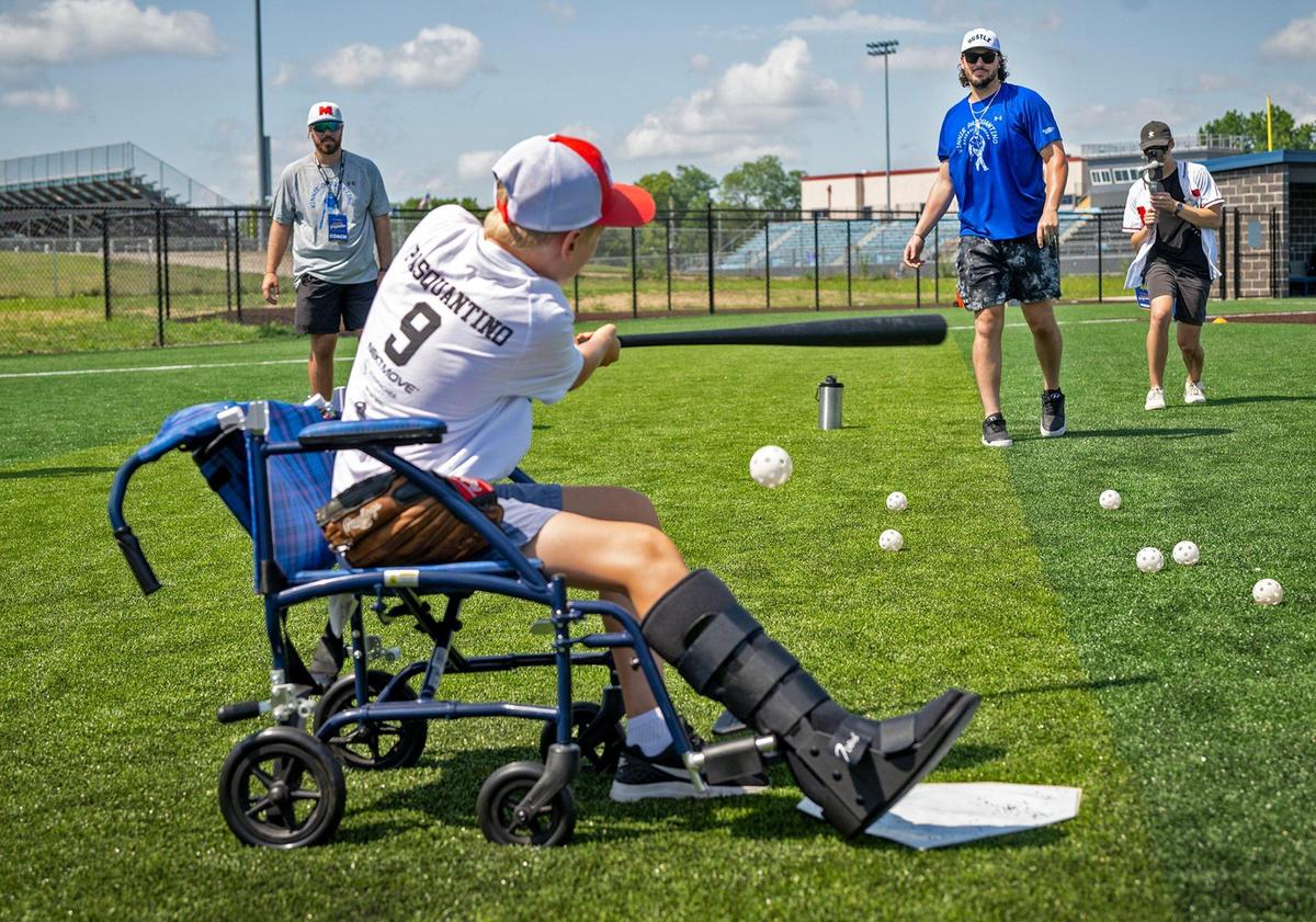 Kansas City Royals first baseman Vinnie Pasquantino, pitched as Noah Farrow, 13, hit the ball during the Vinnie Pasquantino Baseball ProCamp at Grandview High School on Thursday, July 10, 2025, in Grandview, Missouri. Noah, who broken his leg on Sunday, was still able to bat and participate in the camp.