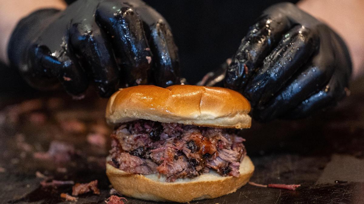 Harp Barbecue cook Chris Johnson constructs a chopped brisket sandwich at its new location in Overland Park on Wednesday, Nov. 13.