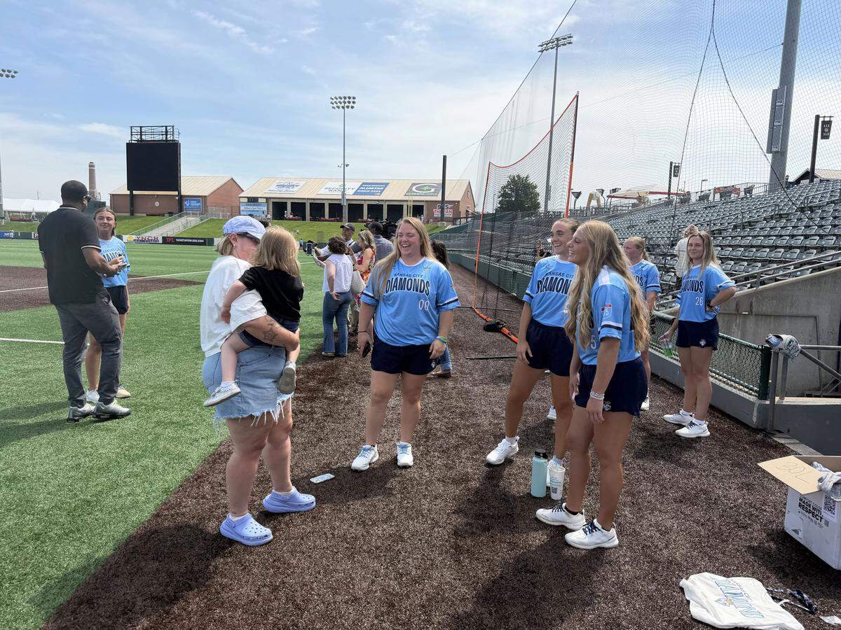 A group of KC Diamonds players stand in a circle around a mom and her young daughter. 