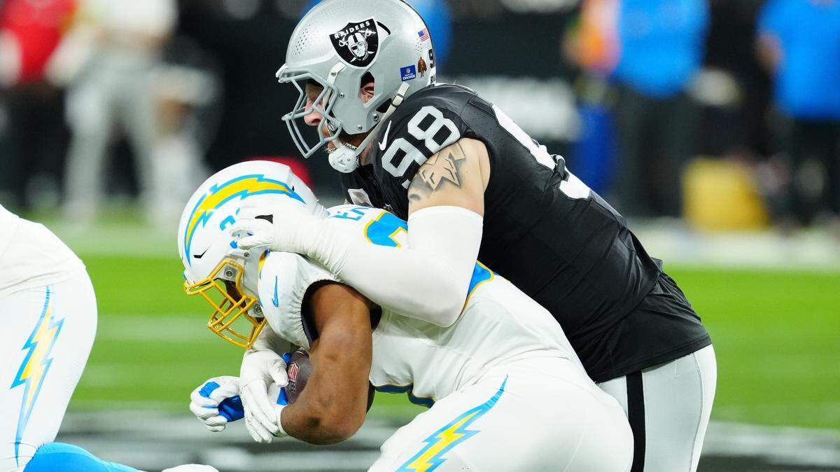 Las Vegas Raiders defensive end Maxx Crosby (98) tackles Los Angeles Chargers running back Austin Ekeler (30) in the first quarter at Allegiant Stadium.