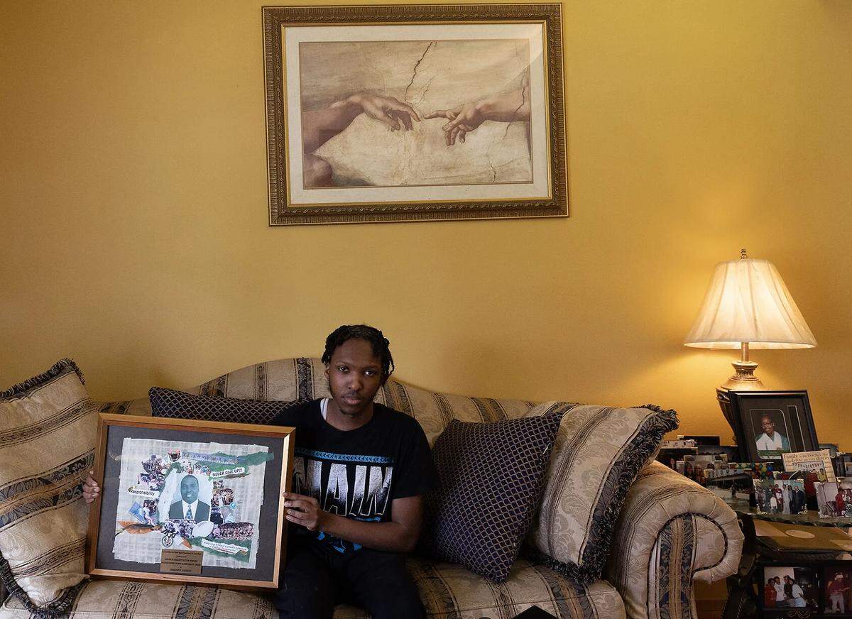 Jalen Allen sits for a portrait while holding a photo collage of his father, Demetrious Johnson, at his home in St Louis. On Dec. 24, 2022, Allen received a text message from Mizzou wide receiver Luther Burden III informing him that Johnson had passed away. “I was calm at first. I didn’t believe it,” Allen said. “Then, I called my mom, and when she told me it was true, I broke down for four or five hours. I couldn’t stop crying.”