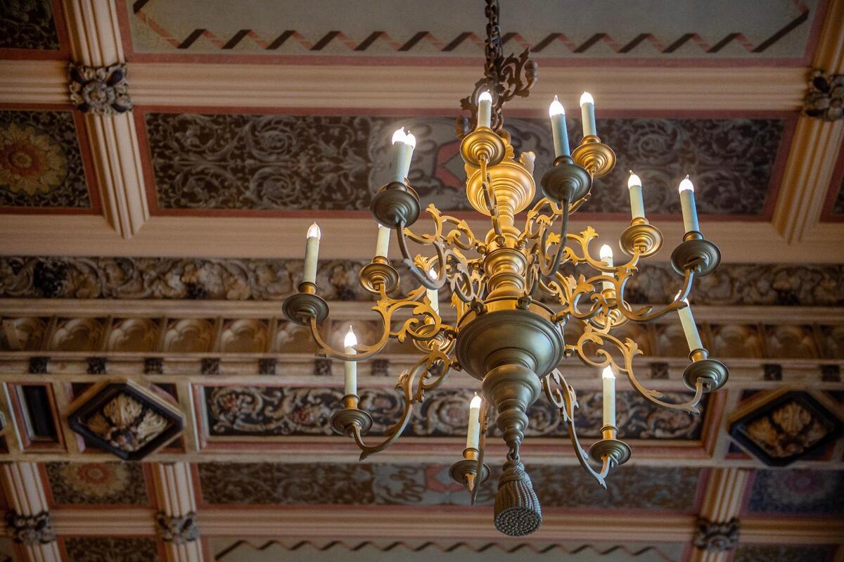 An original chandelier is seen hanging from the ballroom ceiling.