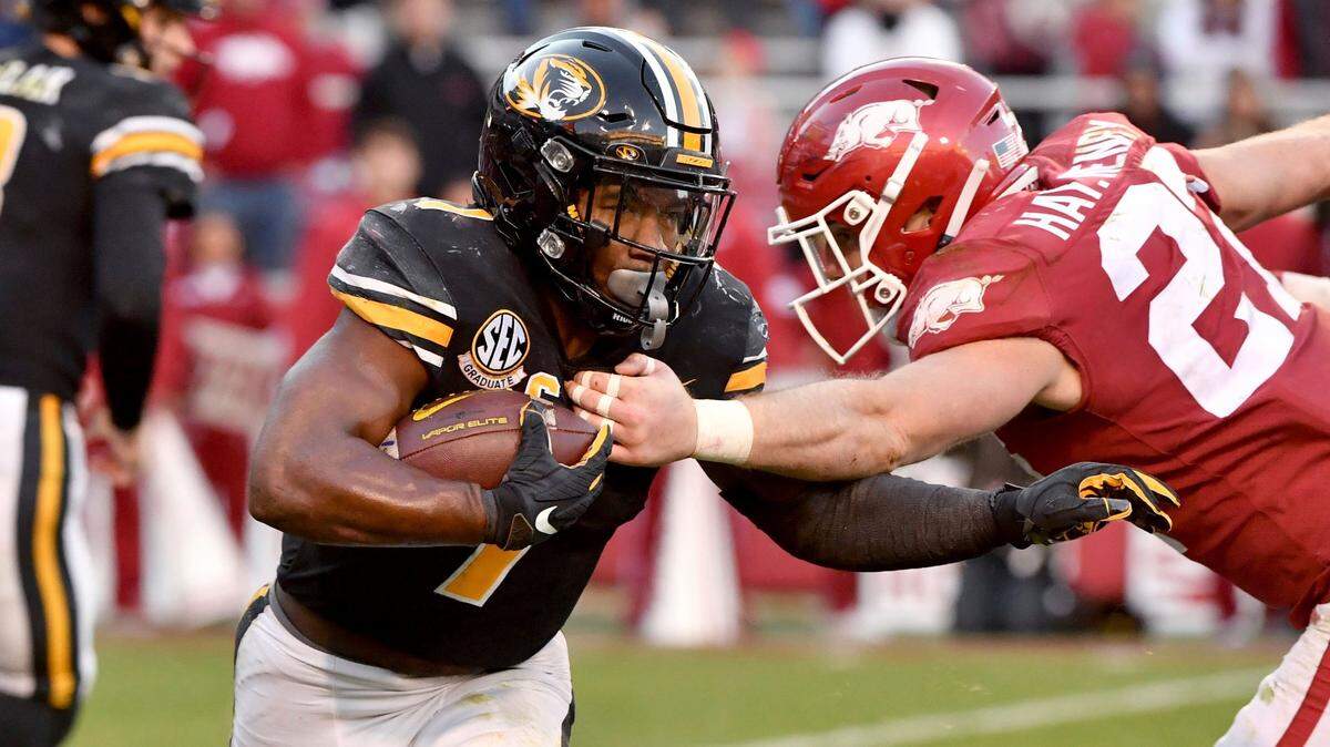Missouri running back Tyler Badie (1) tries to shake Arkansas defensive back Hayden Henry (27) during the second half of an NCAA college football game Friday, Nov. 26, 2021, in Fayetteville, Ark. (AP Photo/Michael Woods)