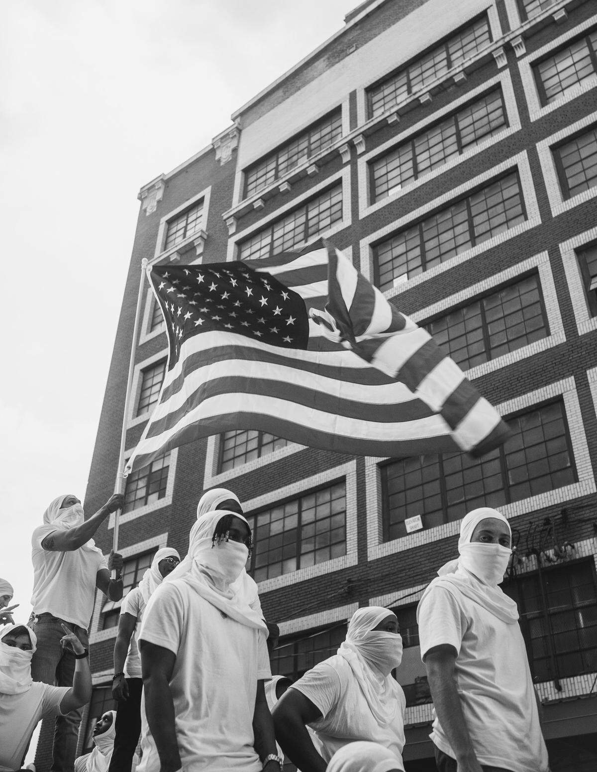 Masked extras stand atop a tank with an American flag waving behind them outside a building in the West Bottoms for A$AP Rocky’s video shoot.