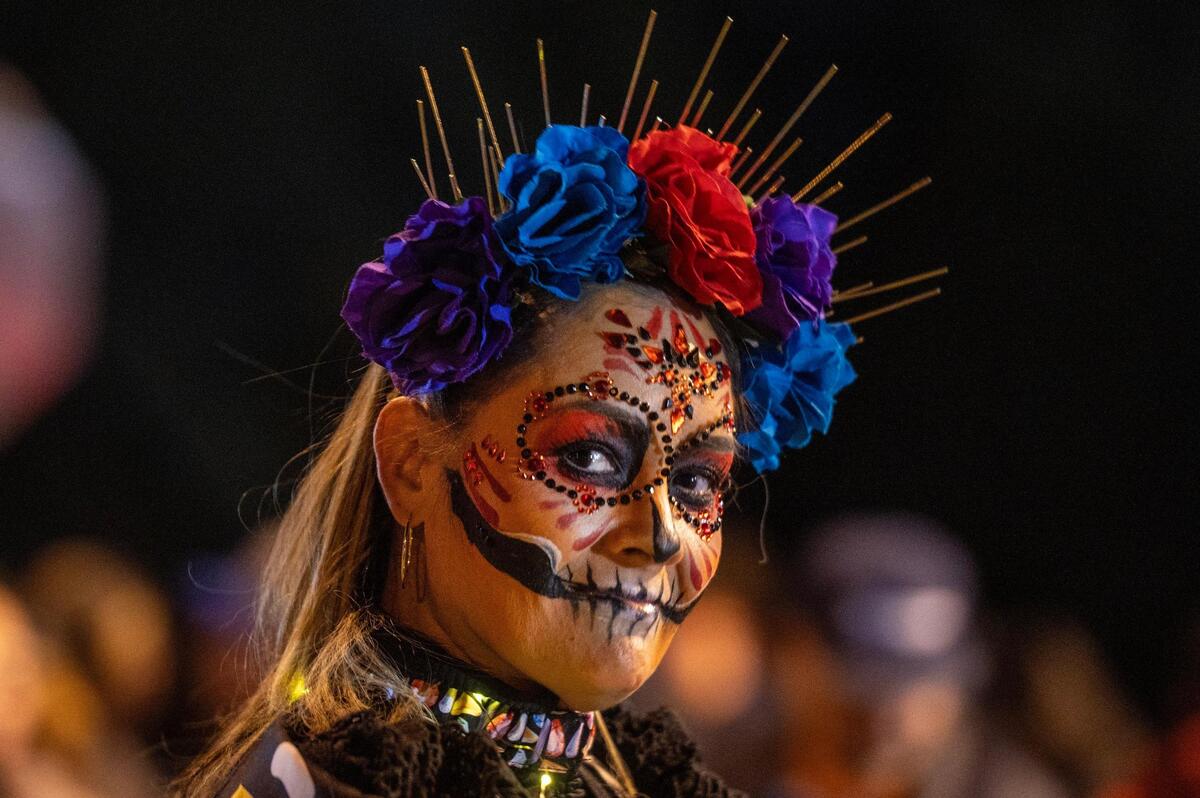A parade participant walks the route in her Catrina costume during the Dia de los Muertos festival parade at the Mattie Rhodes Center.