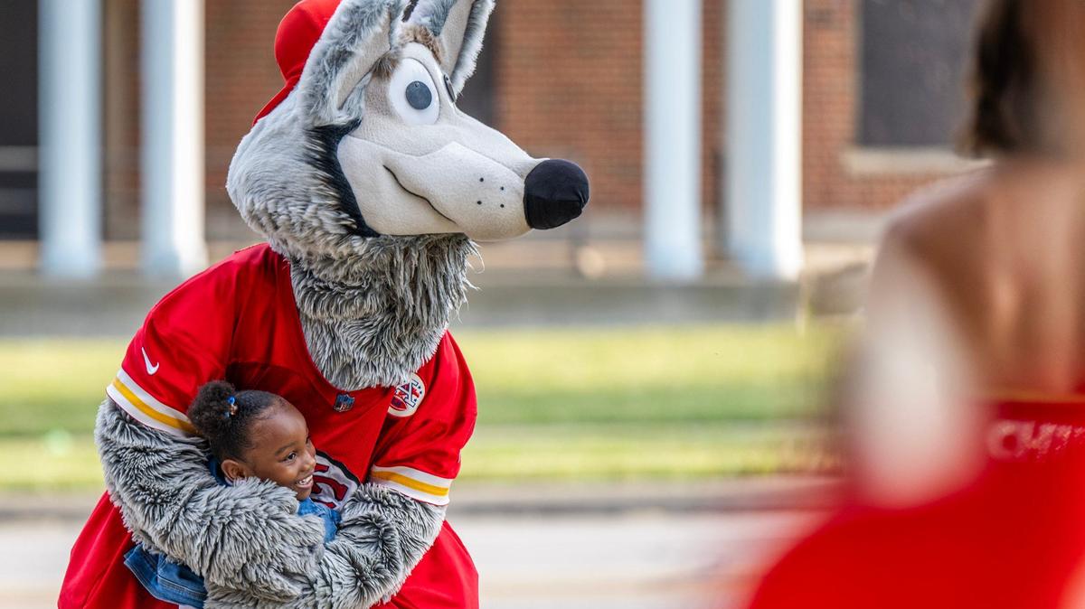 Seven-year-old Kam Brown spots mascot K.C. Wolf and gives him a hug while dropping off her sister with grandma Wendy Mitchem for the first day of school at Central Middle School on Monday, Aug. 19, 2024, in Kansas City.