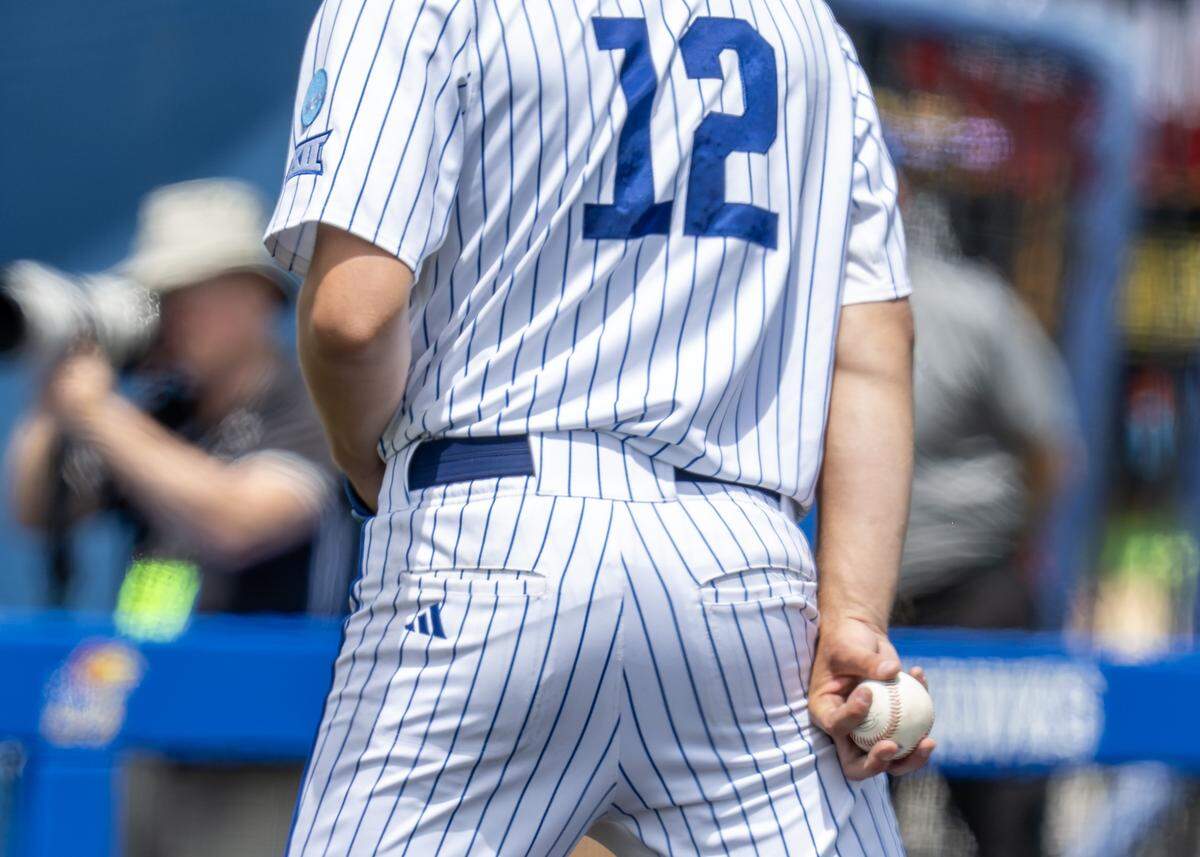 Kansas Jayhawks pitcher Dominic Voegele (12) holds the ball before a throw in the seventh inning against the Northeastern Huskies during an NCAA baseball tournament game at Hoglund Ballpark on Friday, May 29, 2026, in Lawrence.