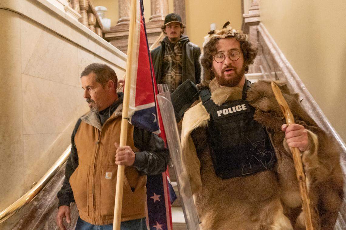 Supporters of President Donald Trump, one of them carrying a confederate flag, walk down the stairs outside the Senate Chamber as violence erupted at the Capitol after demonstrators breached the security and stormed the U.S. Capitol, Wednesday, Jan. 6, 2021 in Washington.