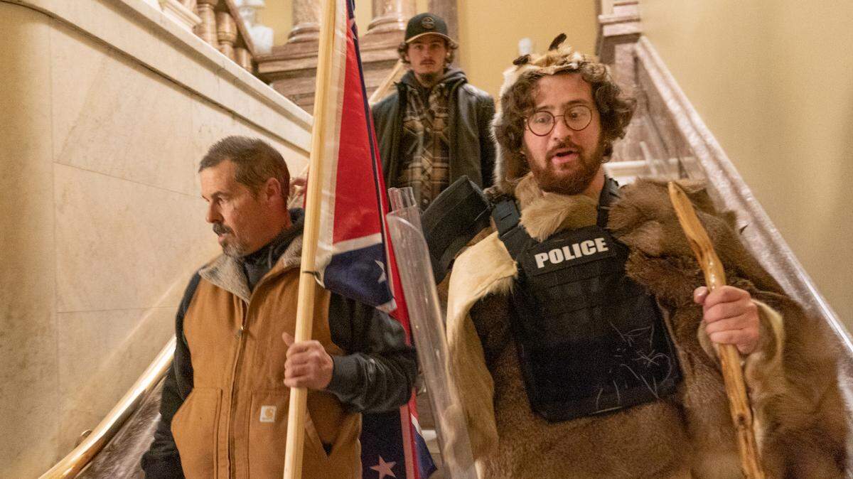 Supporters of President Donald Trump, one of them carrying a confederate flag, walk down the stairs outside the Senate Chamber as violence erupted at the Capitol after demonstrators breached the security and stormed the U.S. Capitol, Wednesday, Jan. 6, 2021 in Washington.