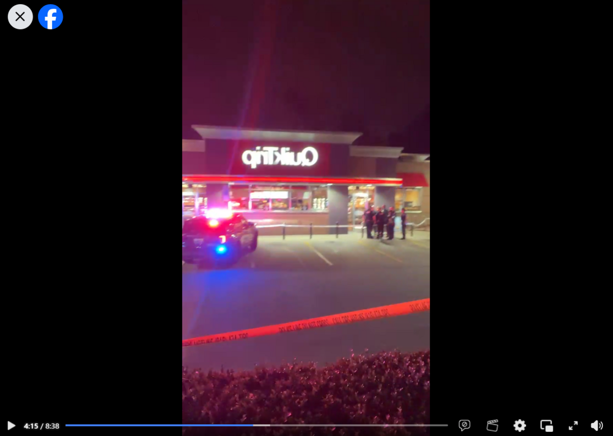 Police officers stand outside the Westport Road QuikTrip after a shooting killed a man and critically injured another, as shown in this screenshot from KC Reel’s Facebook Live.