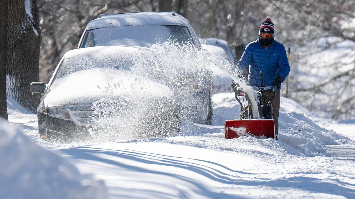 A resident clears snow along a parked vehicle on Monday in Kansas City. The snow and a cold air mass that has locked in place over the region has led to dangerously frigid temperatures.