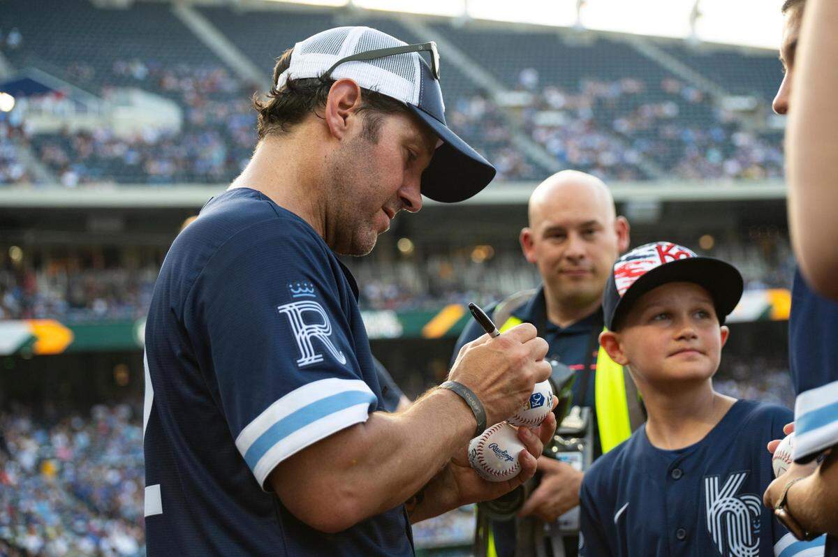 Paul Rudd signs a fan’s ball at Kauffman Stadium on Friday.