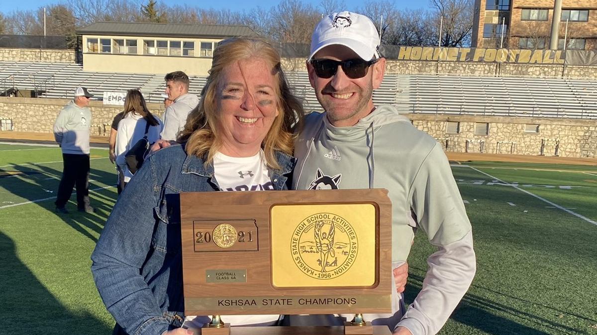 Blue Valley Northwest principal Amy Pressly and coach Clint Rider celebrate with the Kansas Class 6A football trophy after the Huskies beat Derby at Emporia State last weekend.