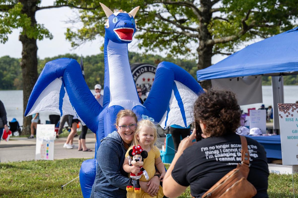 Cat Hummel holds her two-year-old niece, Hazel, as her mother, Carolyn Hummel, takes a photo in front of an inflatable dragon during the KC Dragon Boat Festival on Saturday, Sept. 28, 2024, at Shawnee Mission Park.