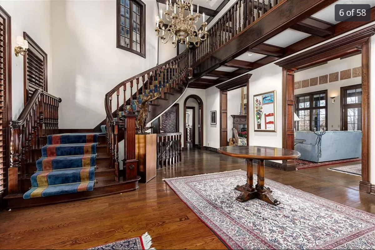 The entryway and curved wooden staircase of the home for sale at 11409 Meadow Lane in Leawood are seen in this listing photo.