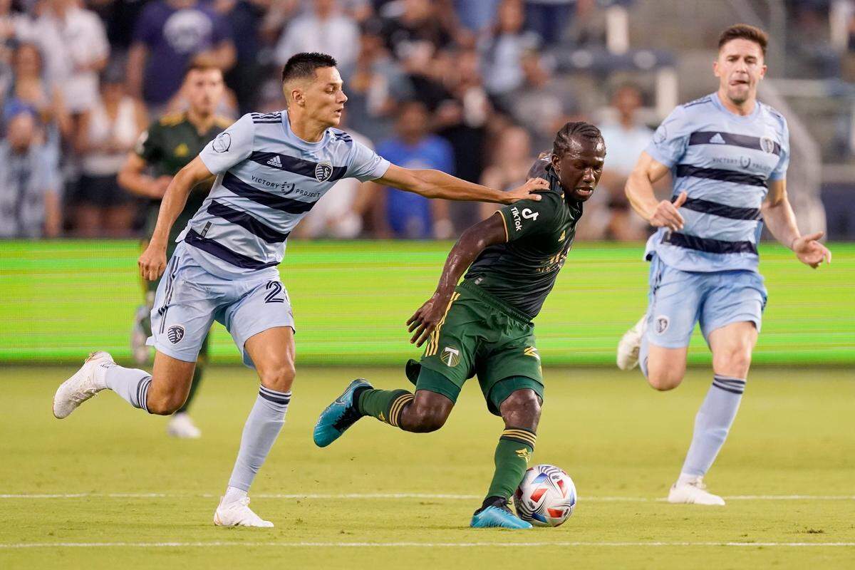 Sporting Kansas City forward Daniel Salloi, left, and Portland Timbers midfielder Diego Chara (21) chase after the ball during the first half of an MLS soccer match Wednesday, Aug. 18, 2021, in Kansas City, Kan.