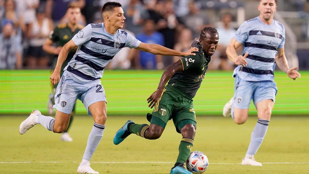 Sporting Kansas City forward Daniel Salloi, left, and Portland Timbers midfielder Diego Chara (21) chase after the ball during the first half of an MLS soccer match Wednesday, Aug. 18, 2021, in Kansas City, Kan.