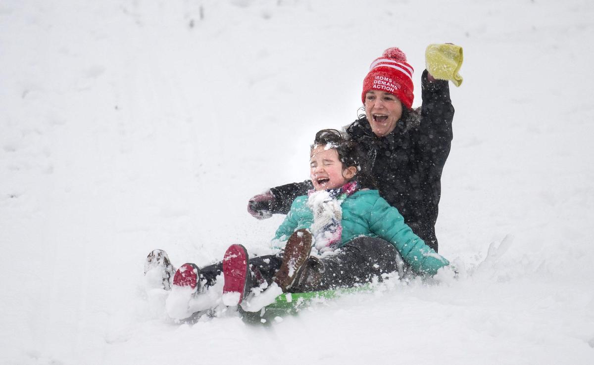 Erin Gingrich-Gaylord sleds down the Brookside Hill with her 7-year-old daughter Maebe Overright on Tuesday, Jan. 9, 2024, in Kansas City.
