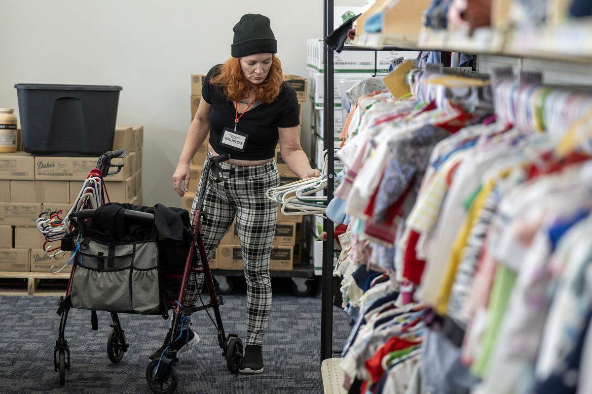 Volunteer Christina, a former client, removes hangers from racks of clothes to restock at the Starfish Project, a non-profit that provides essentials for free to those in need, on Thursday, Feb. 12, 2026, in Olathe. “They help so many people,” Christina said. “They helped me many times.” She volunteers three days a week.