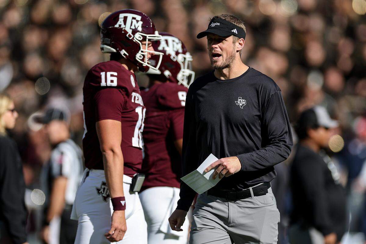Texas A&M offensive coordinator Collin Klein, right, watches warm-ups before a college football game against the Samford Bulldogs at Kyle Field in College Station, Texas on Nov. 22, 2025.