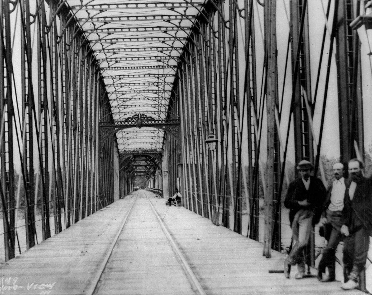 Designer and civil engineer Octave Chanute (middle) standing atop the wooden planks on the completed Hannibal Bridge in 1869.