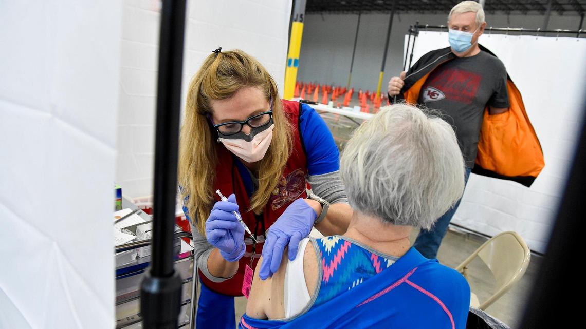 Platte County Health Department nurse Karla Hunt administers a COVID-19 vaccine to Annie Brown of Smithville. Brown’s husband James Brown removes his jacket to get ready for his vaccine. The Platte County Health Department opened a mass vaccination clinic in an unused warehouse in the Horizons Industrial Park in Riverside Tuesday, Mar. 2, 2021. The space was donated by NorthPoint Development.