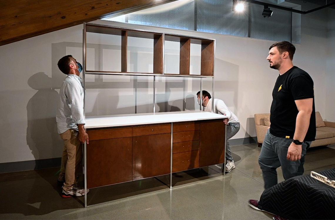 Paul Churchill, left and his son, Henry, moved a 1959 modular kitchen cabinet designed by Paul McCobb into place as owner Samuel Hildreth, right, looked on as they prepared for an exhibit featuring furniture and household items from the mid-century modern designer. The exhibit, Paul McCobb-America’s Favorite Designer, features items from Hildreth’s private collection and it will open Saturday, May 22, at Johnson County Museum at the Johnson County Arts & Heritage Center in Overland Park.