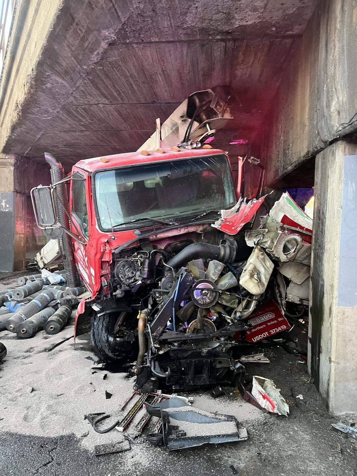 A semi hauling roofing materials was severely damaged after striking the infamous, low-clearance Independence Avenue “truck-eating” bridge in Kansas City, spilling supplies Monday morning. The driver suffered non-life-threatening injuries to his hand.