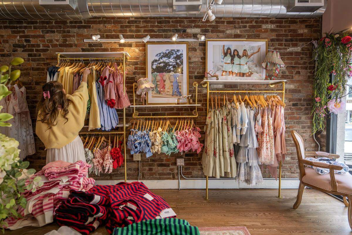 Avery Taylor, co-owner of Ave and Liv, arranges clothing on a rack on Thursday, April 30, 2026, in Parkville.