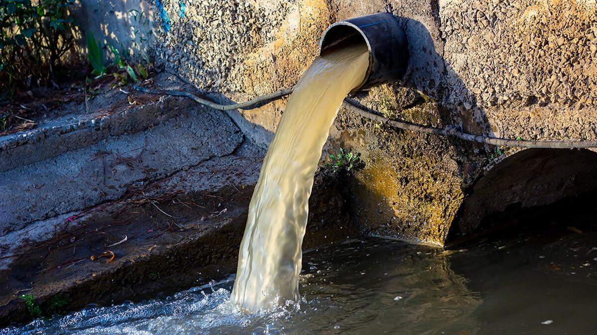 Wastewater sewage pipe dumps the dirty contaminated water into the river. Water pollution, environment contamination 