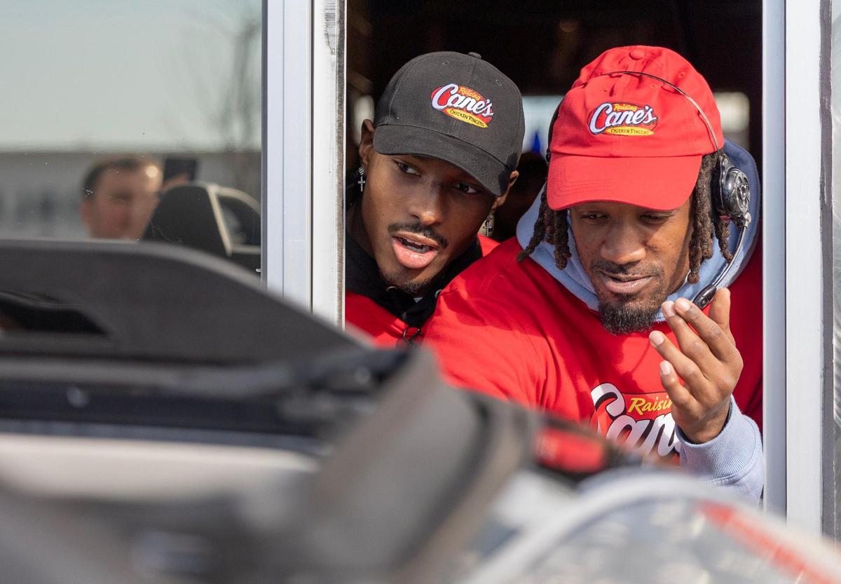 Kansas City Chiefs receiver Mecole Hardman Jr. left, and cornerback L’Jarius Sneed talk to customers while working the the drive through at a Raising Cane’s restaurant in Blue Springs on Tuesday.
