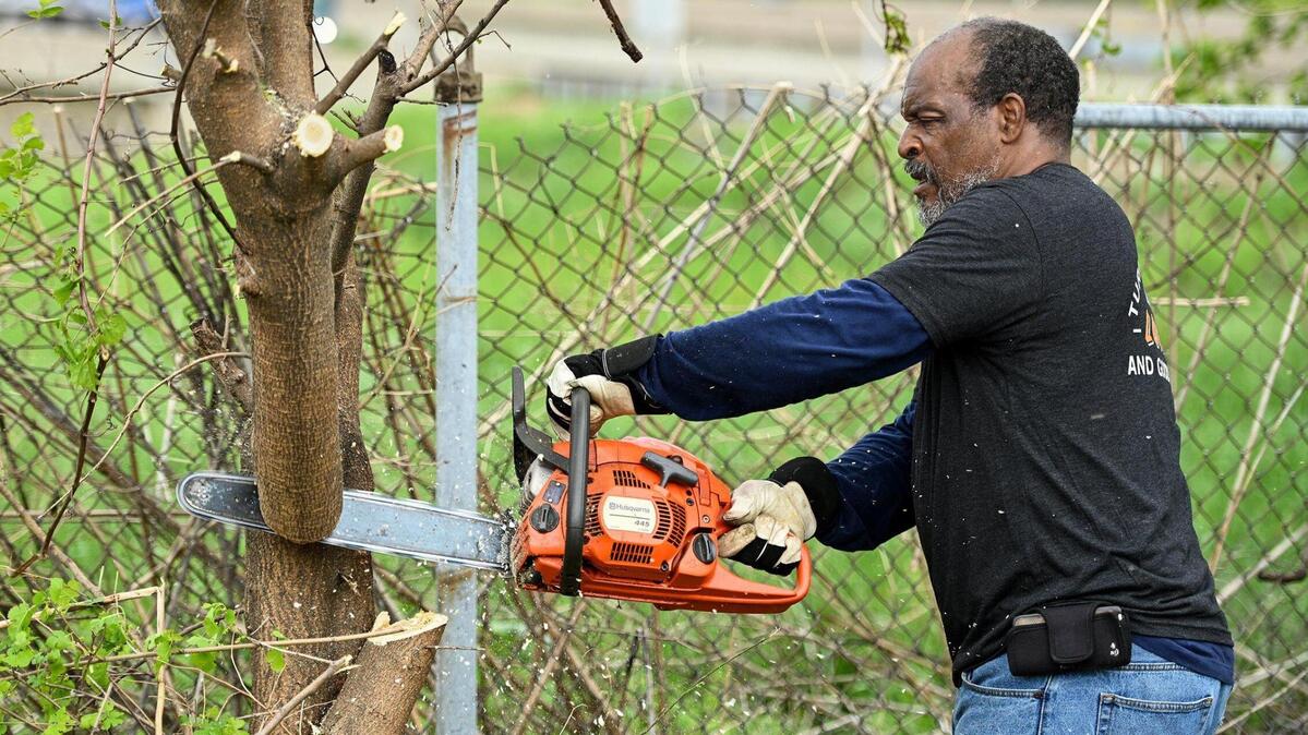 Theodore “Priest” Hughes with Kansas City Community Gardens saws a branch off before cutting the tree down in an effort to help clear the fence line. A small army of volunteers helped give Freeway Park Community Garden in Kansas City’s historic Northeast a makeover for its 20th anniversary. The garden, near E. 14th Street and Indiana Avenue, is managed by Kansas City Community Gardens, which rents plots to neighborhood gardeners.