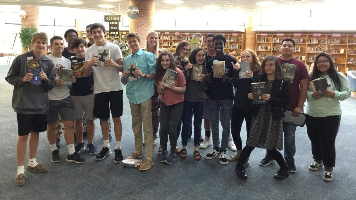 Shawnee Mission Northwest High School students hold up novels of their choice at their school library. Circulation at the library has doubled in the past years after teachers worked with librarian Meghan Stigge to revise how they approached reading assignments.