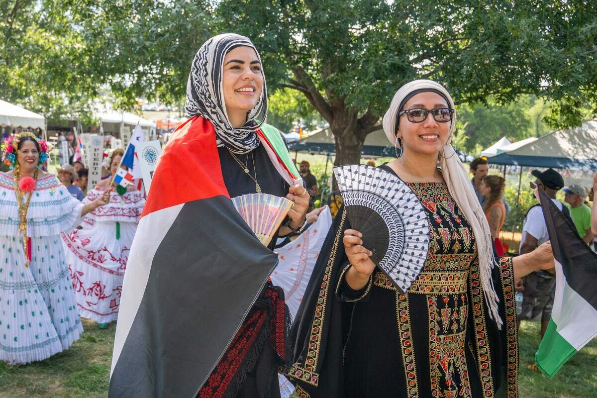 Two women wrapped in the Palestinian flag walk in the parade of flags at the Ethnic Enrichment Festival in Swope Park on Saturday.
